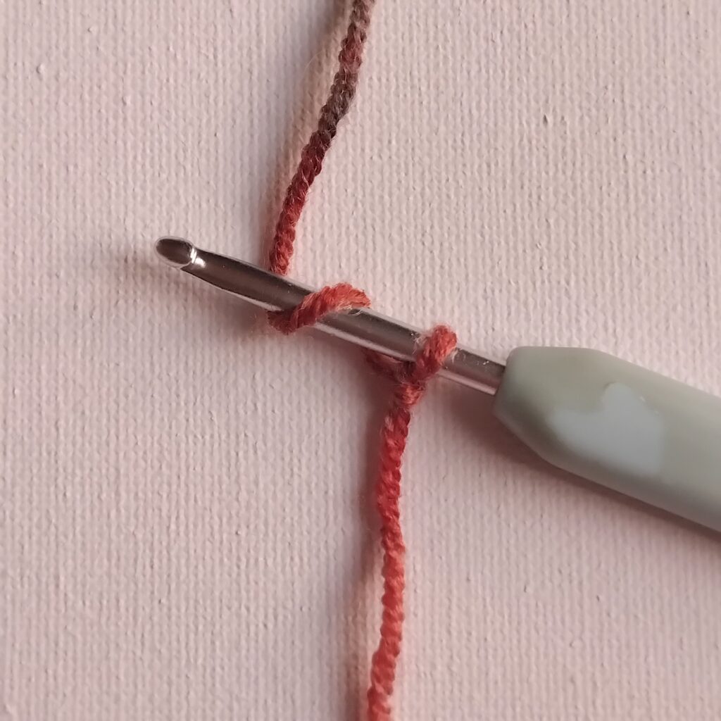photo showing a slip knot on a crochet hook and the yarn wrapped around